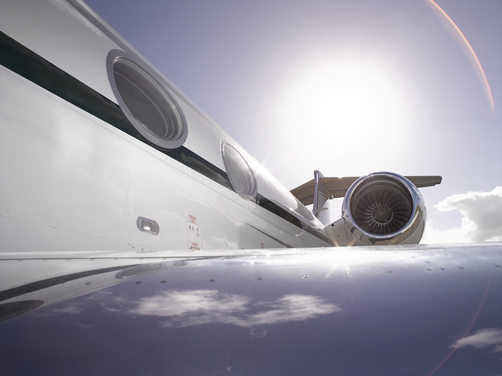 Sun rising over flying private jet wing