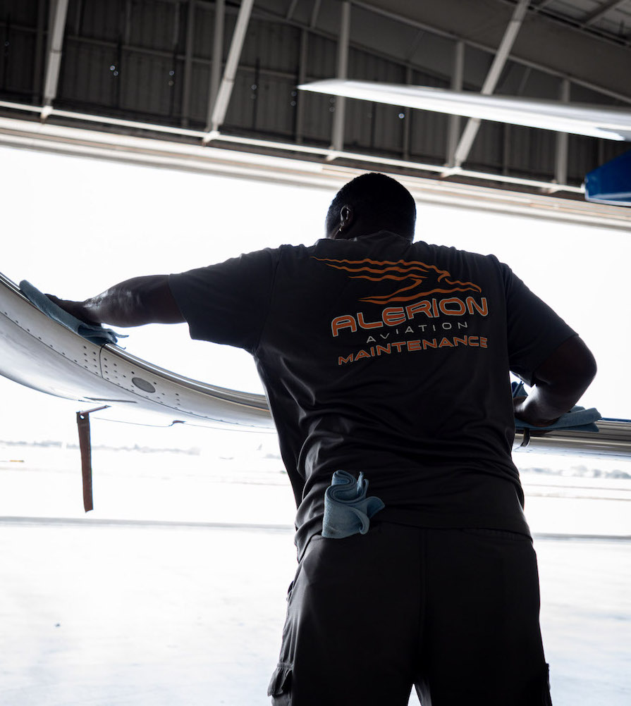 aircraft mechanic cleaning a wing of a private jet